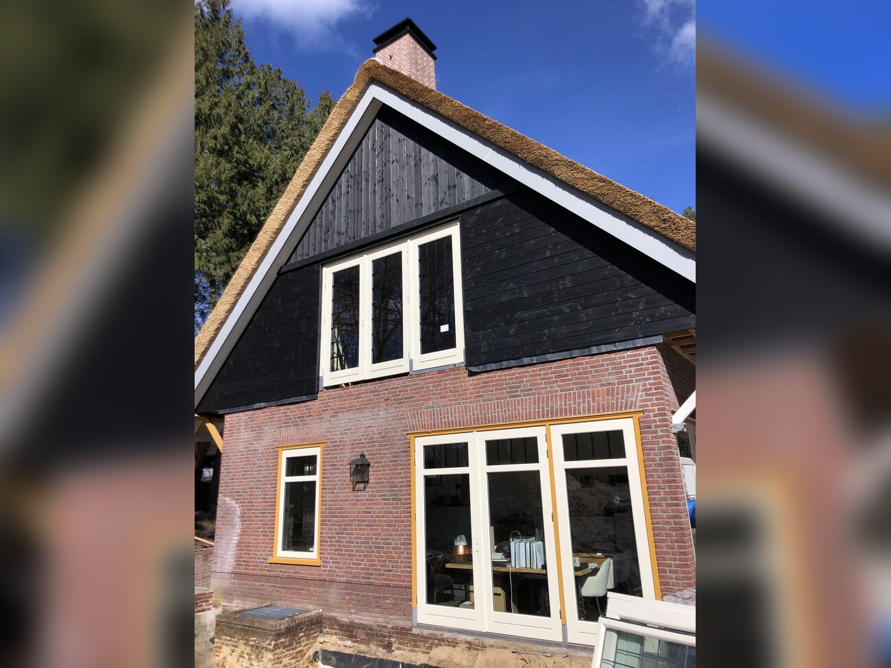 Gevel met rieten kap, zwarte houten gevelbekleding en nieuw geplaatste kozijnen